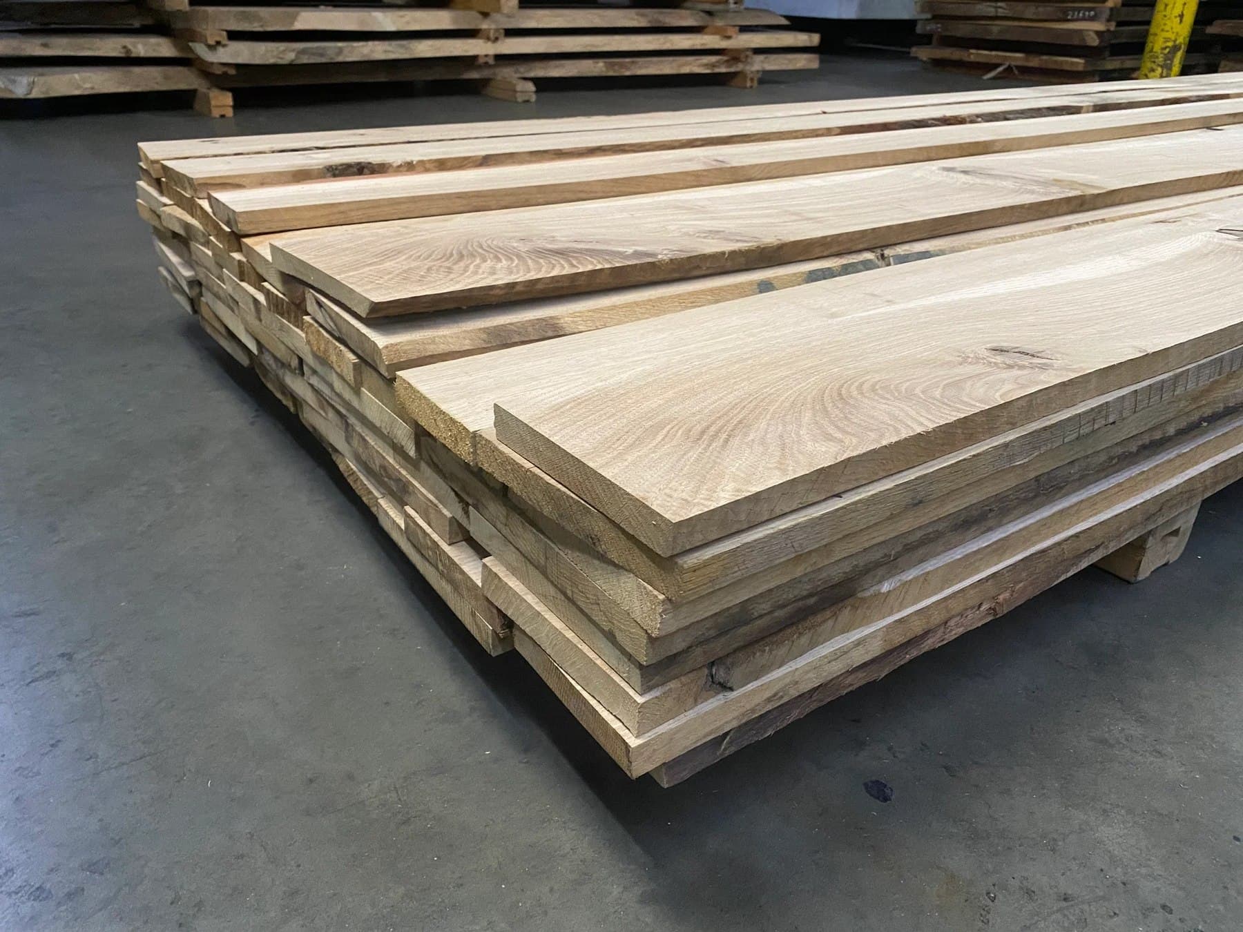 Freshly milled white oak boards stacked on a pallet, showing the straight grain and ray fleck