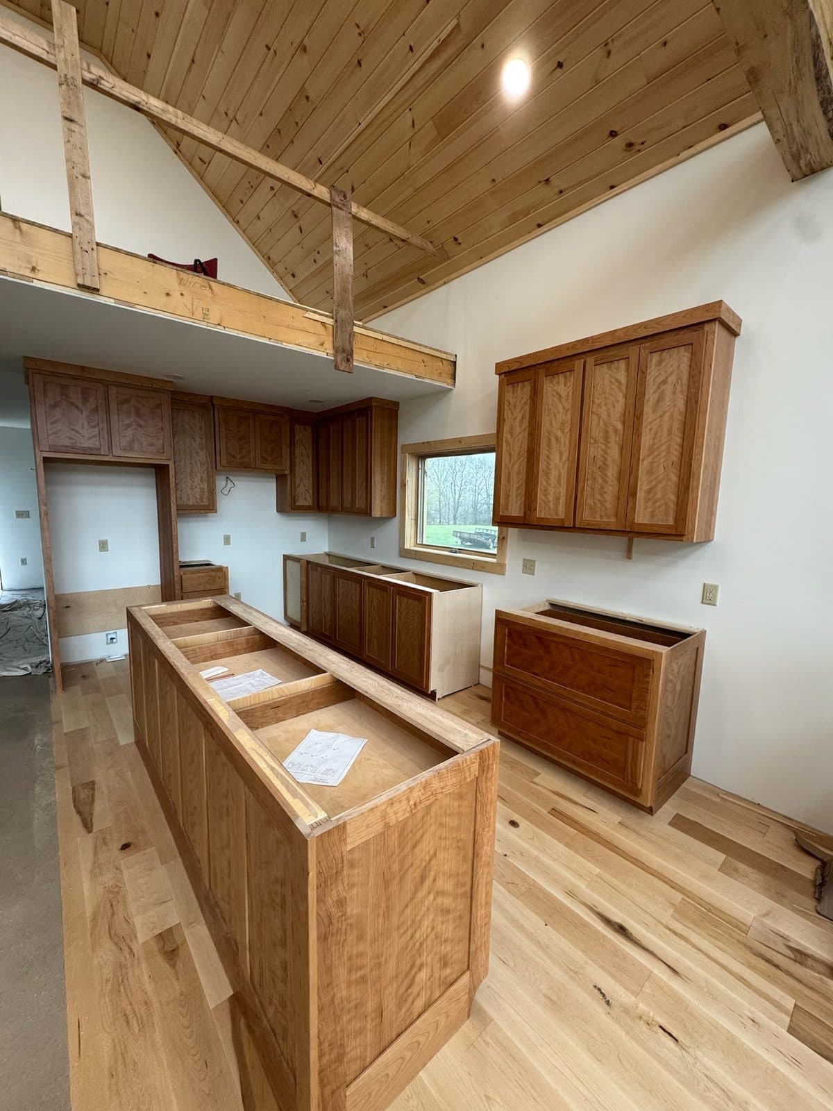 Curly cherry kitchen under a vaulted pine ceiling